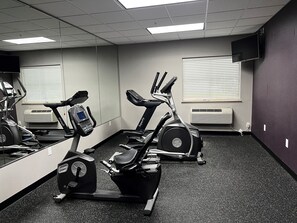 A gym with stationary bikes, treadmills, and a mirrored wall. - Baymont by Wyndham College Station (College Station)