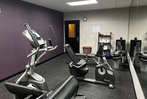 A gym with stationary bikes, a treadmill, and weight machines. - Baymont by Wyndham College Station (College Station)
