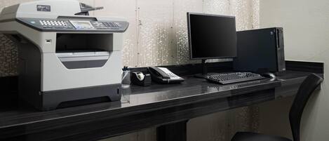 Ein moderner Schreibtisch mit Drucker, Bildschirm, Tastatur und Telefon.