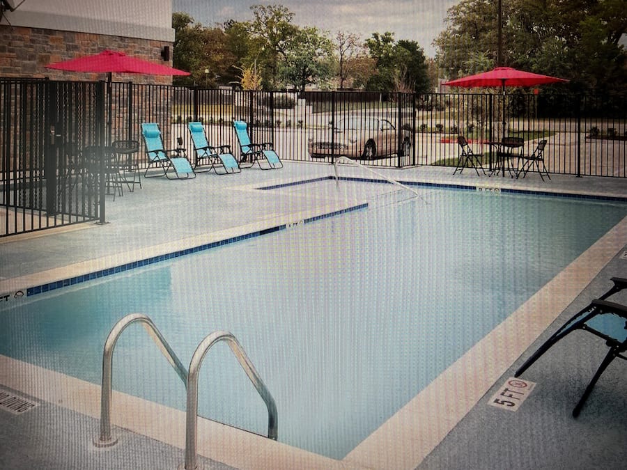 Una piscina al aire libre, sombrillas, sillones reclinables de piscina
