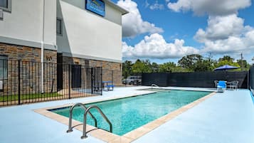 Una piscina al aire libre, sombrillas, sillones reclinables de piscina