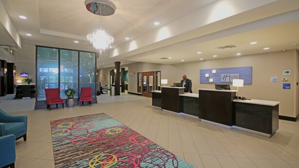 A hotel lobby with a reception desk, seating area, and a large window. - Holiday Inn Express & Suites Charlotte North by IHG (Charlotte)