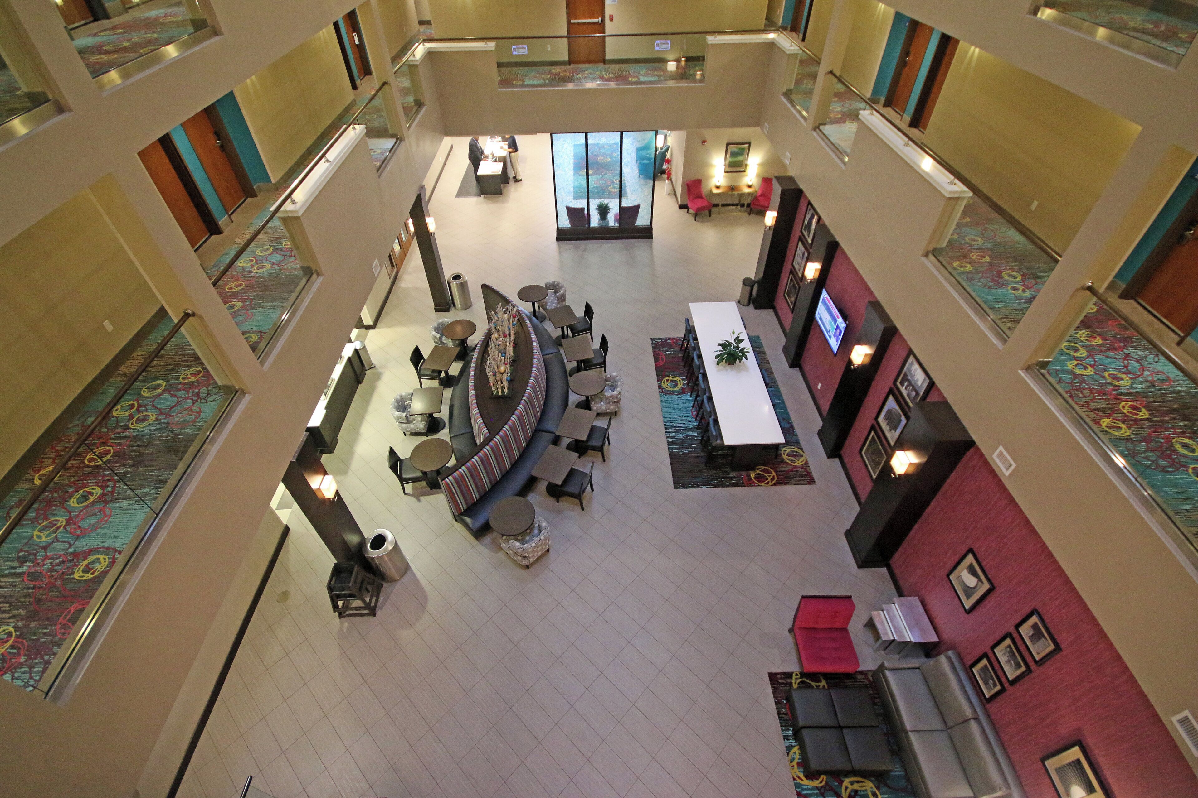 A multi-level hotel lobby with a central seating area, multiple tables, and a reception desk.