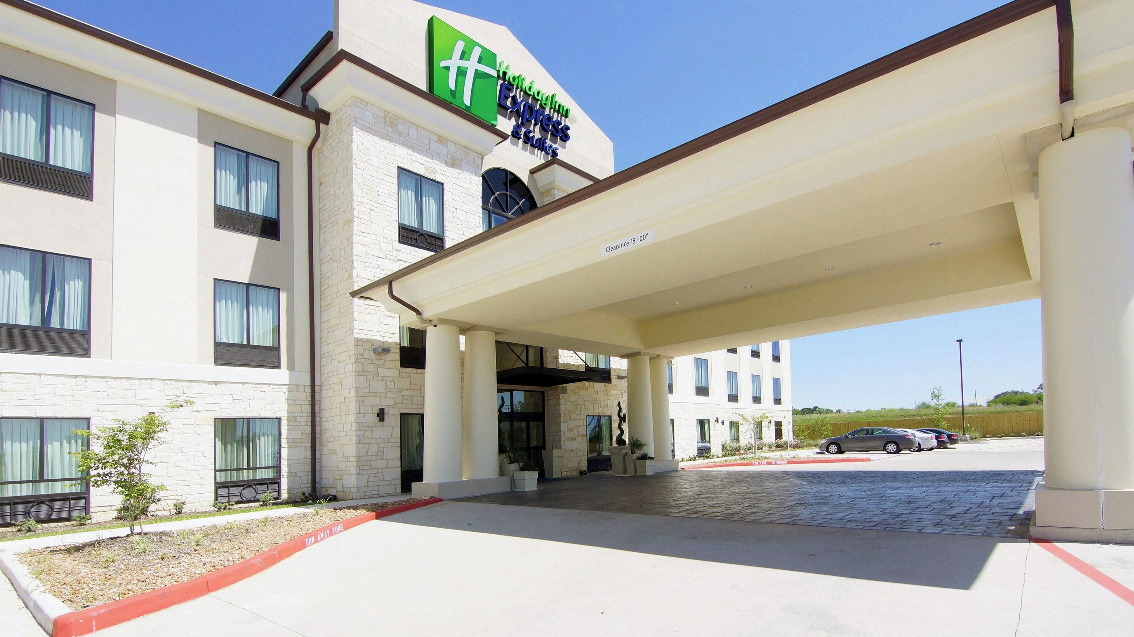 A hotel with a clear sign for 'Hotellinn Express & Suites' and a covered parking area.