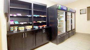 Une petite cuisine équipée d’un congélateur, d’étagères remplies de collations et de boissons, et d’un réfrigérateur.