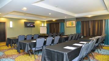 A conference room with tables and chairs, a projector screen, and a whiteboard.