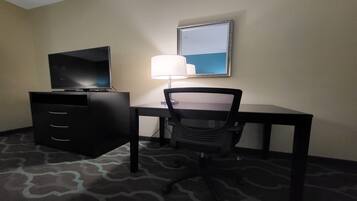 Una habitación de hotel con escritorio, silla, televisor y lámpara.