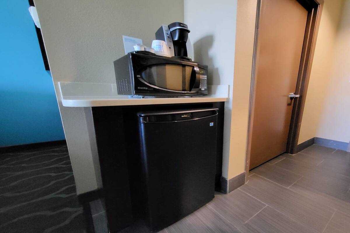 A compact kitchenette with a microwave, coffee maker, and a small refrigerator.