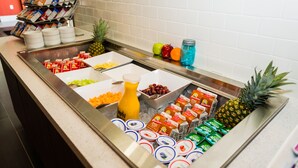 Monipuolinen buffet, jossa on tarjolla erilaisia ruokia ja juomia, kuten hedelmiä, mehuja ja maitotuotteita.