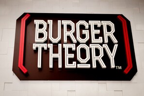 En skylt med texten ”BURGER THEORY” i fet, vit stil mot en mörk bakgrund.