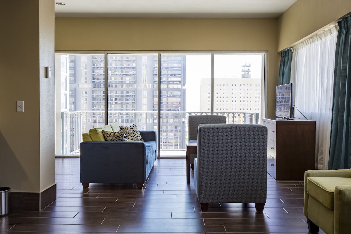 A modern living room with a sofa, armchair, and a TV on a wooden cabinet.