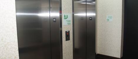 A hallway with two elevators, a non-smoking sign, and a fire safety sign.