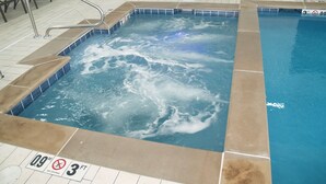 Un bain à remous doté d’un bord carrelé et d’un panneau indiquant une profondeur de 0,9 mètre et une profondeur maximale de 3 pieds.
