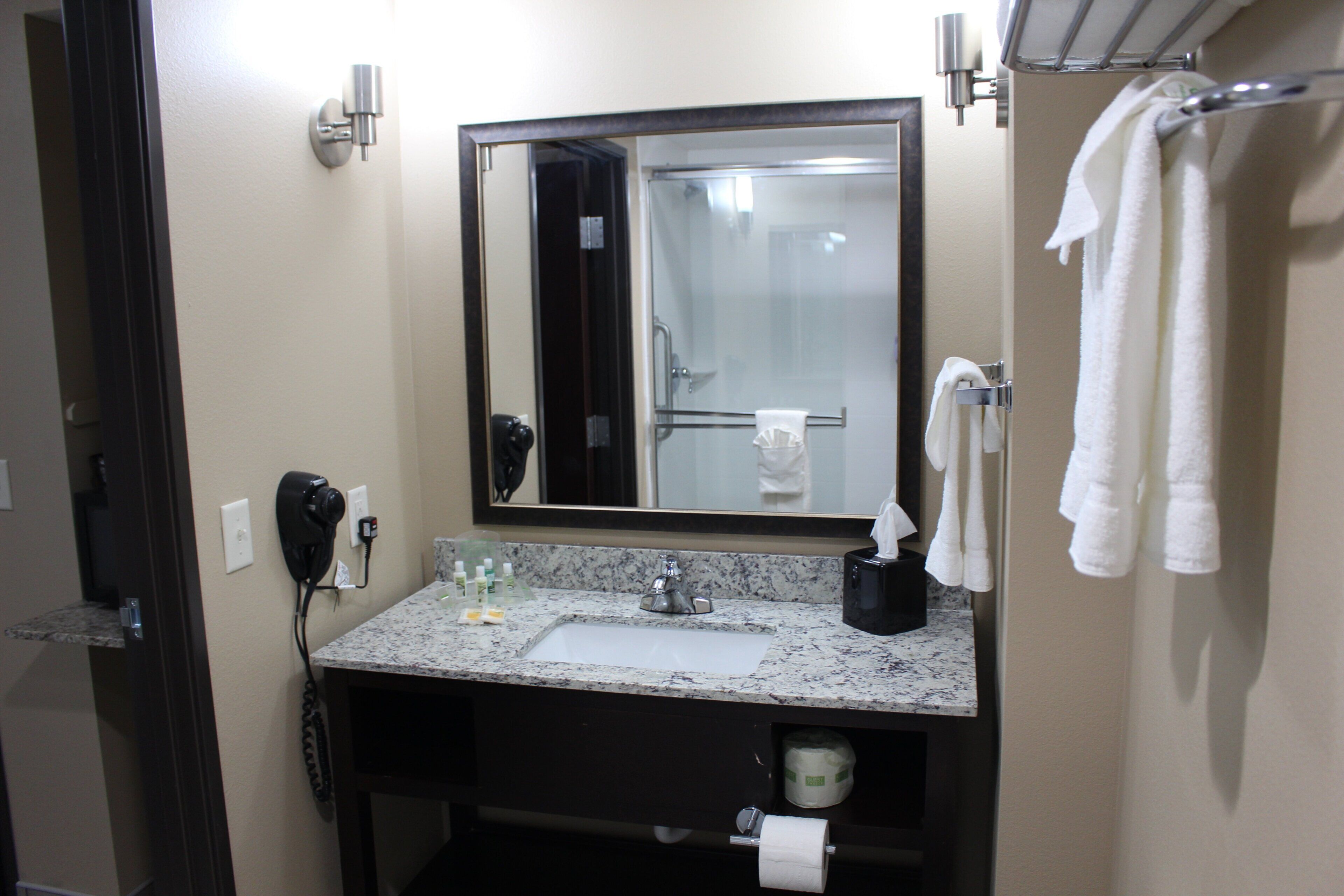 A hotel bathroom with a sink, mirror, towel rack, and a telephone.