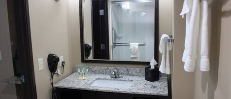 Un bagno d'albergo con lavandino, specchio, portasciuga e telefono.