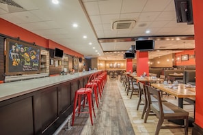 A restaurant with a long counter, red stools, and multiple tables. - Holiday Inn Salina by IHG (Salina)