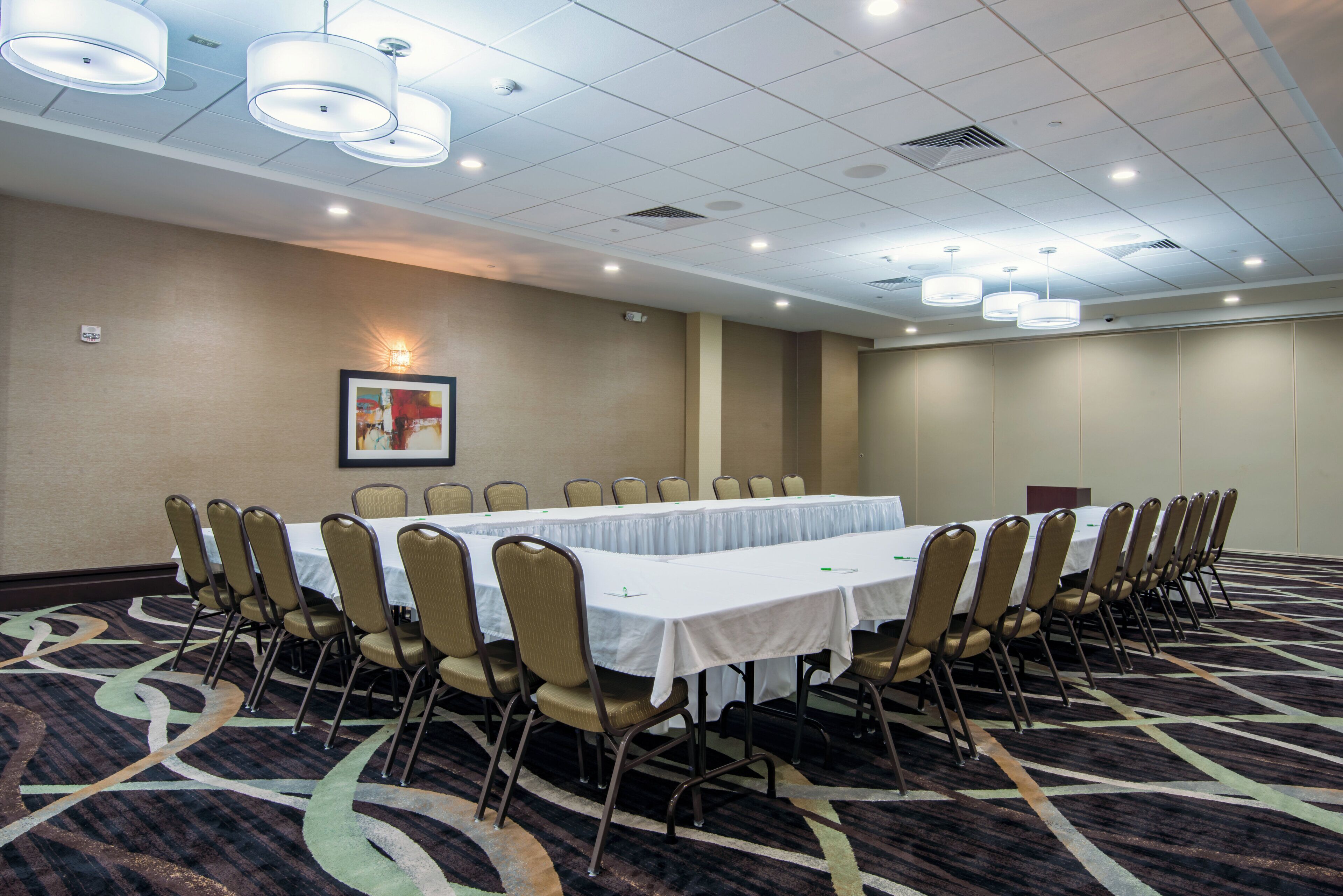 A conference room with a long table, chairs, and a patterned carpet.
