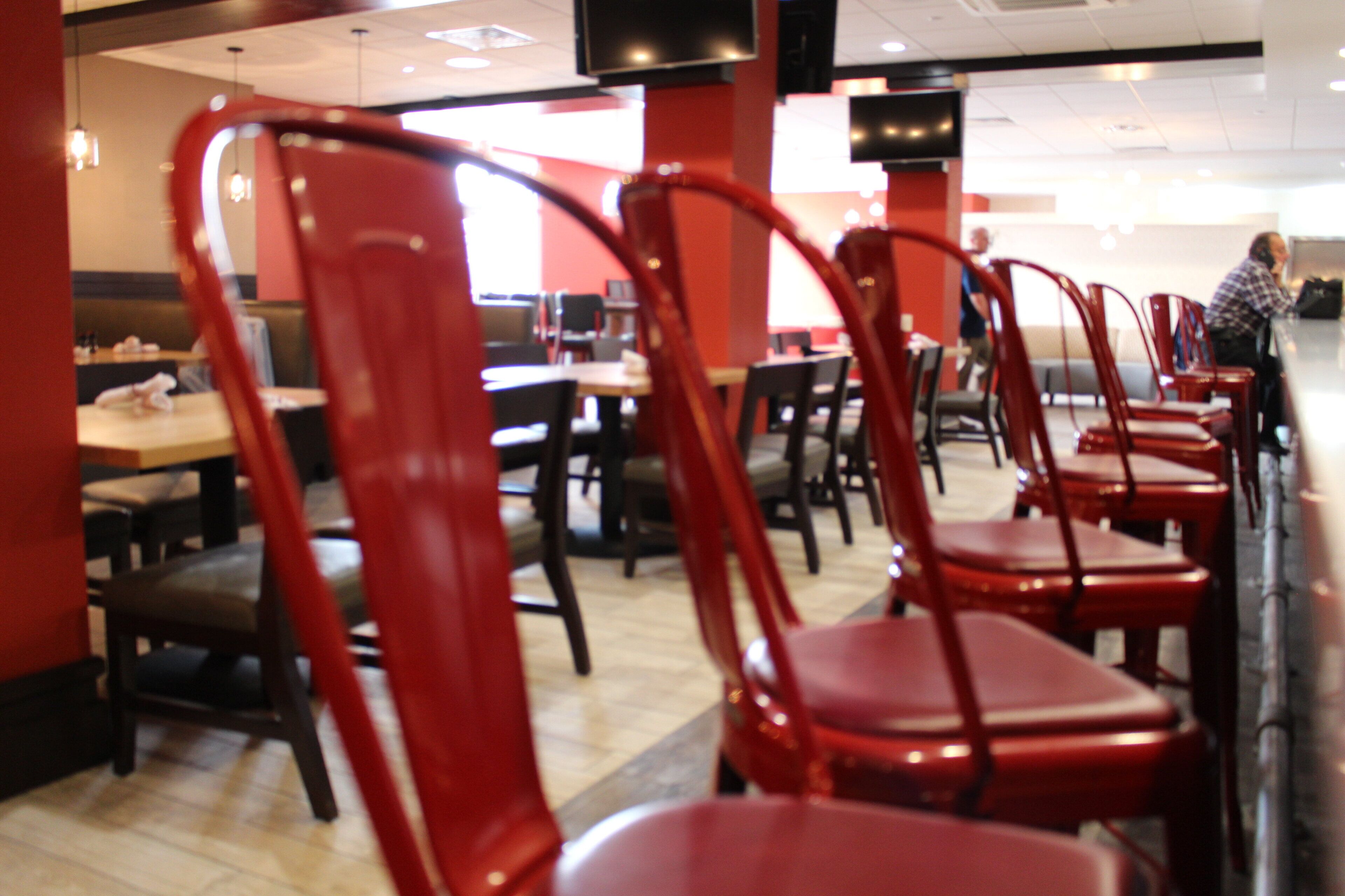 Rows of red chairs and tables in a dining area with a tiled floor.
