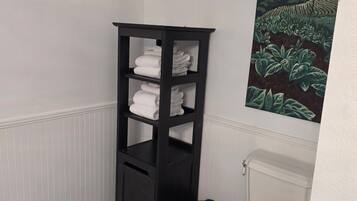 A bathroom with a marble floor, a white toilet, a black towel rack, and a painting on the wall.
