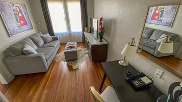 Una sala de estar moderna con un sofá gris, una mesa de comedor con una lámpara y una mesita auxiliar.