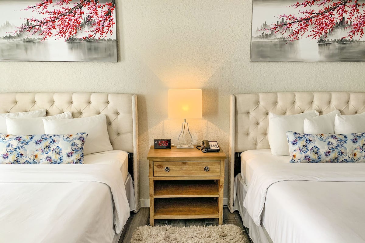 A double bed room with a nightstand, a lamp, and a clock.