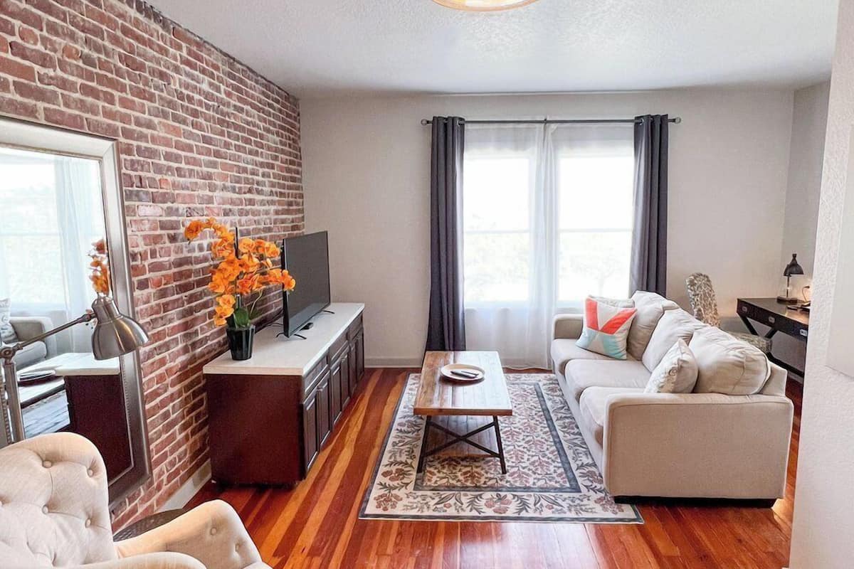 A living room with a brick wall, a sofa, a coffee table, and a TV.