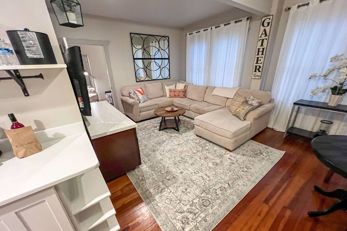 A living room with a beige sectional sofa, a coffee table, a rug, and a TV on a stand.