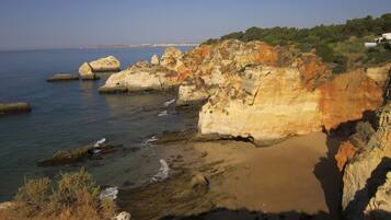 A coastal landscape with rocky formations and a sandy beach.