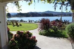 A view of a lake with a grassy area and chairs in the foreground. - Back Bay Inn (Los Osos)
