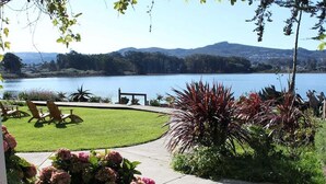 A view of a lake with a grassy area, chairs, and plants. - Back Bay Inn (Los Osos)