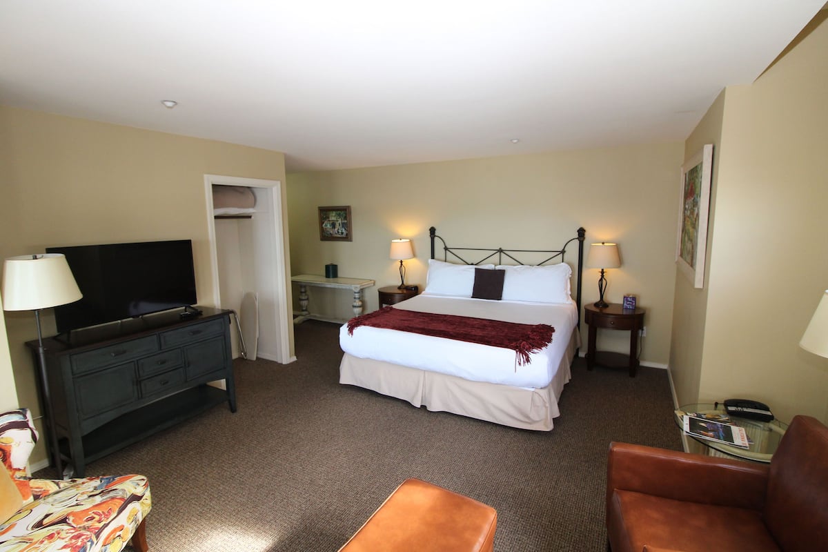 A hotel room with a bed, a television, a desk, and a chair.