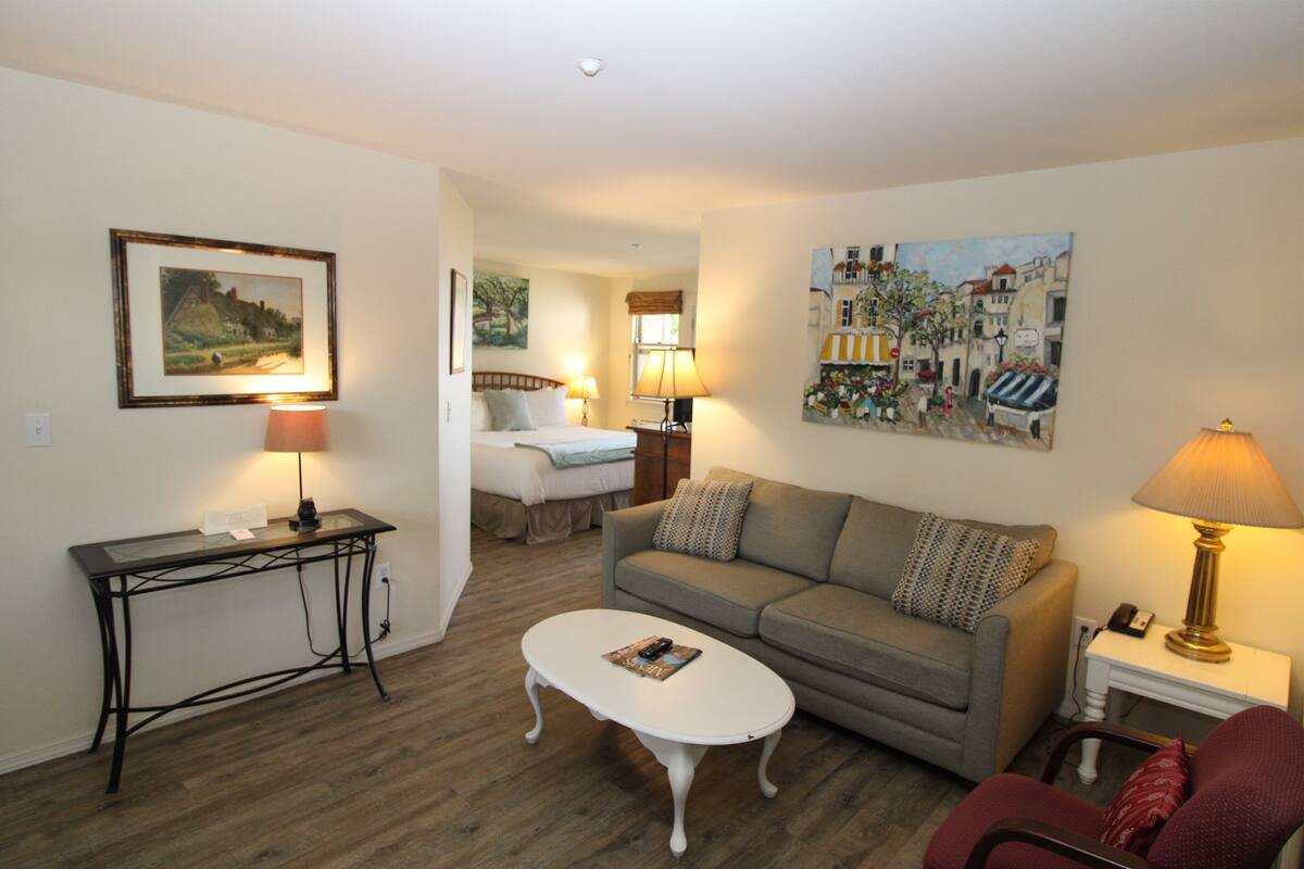 A cozy living room with a sofa, a coffee table, a lamp, and a painting on the wall.