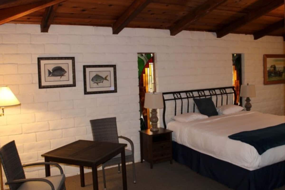 A bedroom with a bed, a nightstand, a chair, and two framed pictures on the wall.