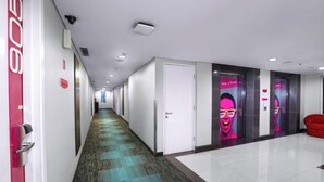 A hotel hallway with a patterned carpet, white walls, and doors leading to rooms. - favehotel Padjajaran Bogor (Bogor)