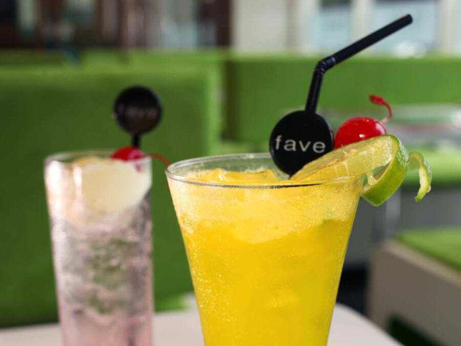 Two cocktails on a table with a green background.