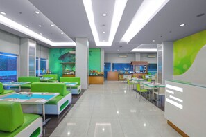 A modern restaurant with green seating, a counter, and a large window. - favehotel Padjajaran Bogor (Bogor)