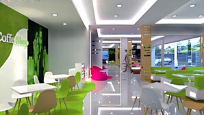 A modern cafe with green and white furniture, a visible menu board, and a person walking in the background. - favehotel Padjajaran Bogor (Bogor)