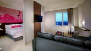 A modern hotel room with a bed, a sofa, a TV, a desk, and a window with a city view. - favehotel Padjajaran Bogor (Bogor)
