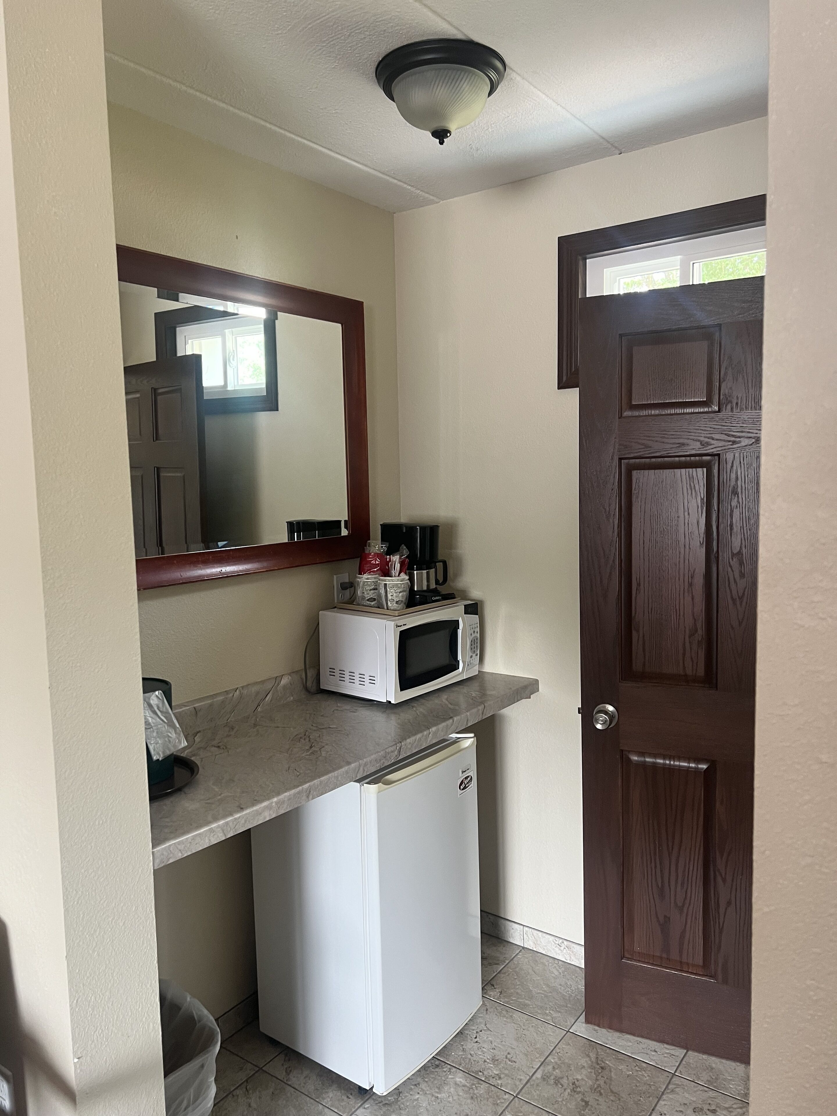 A compact kitchenette with a microwave, a small refrigerator, and a coffee maker on the counter.