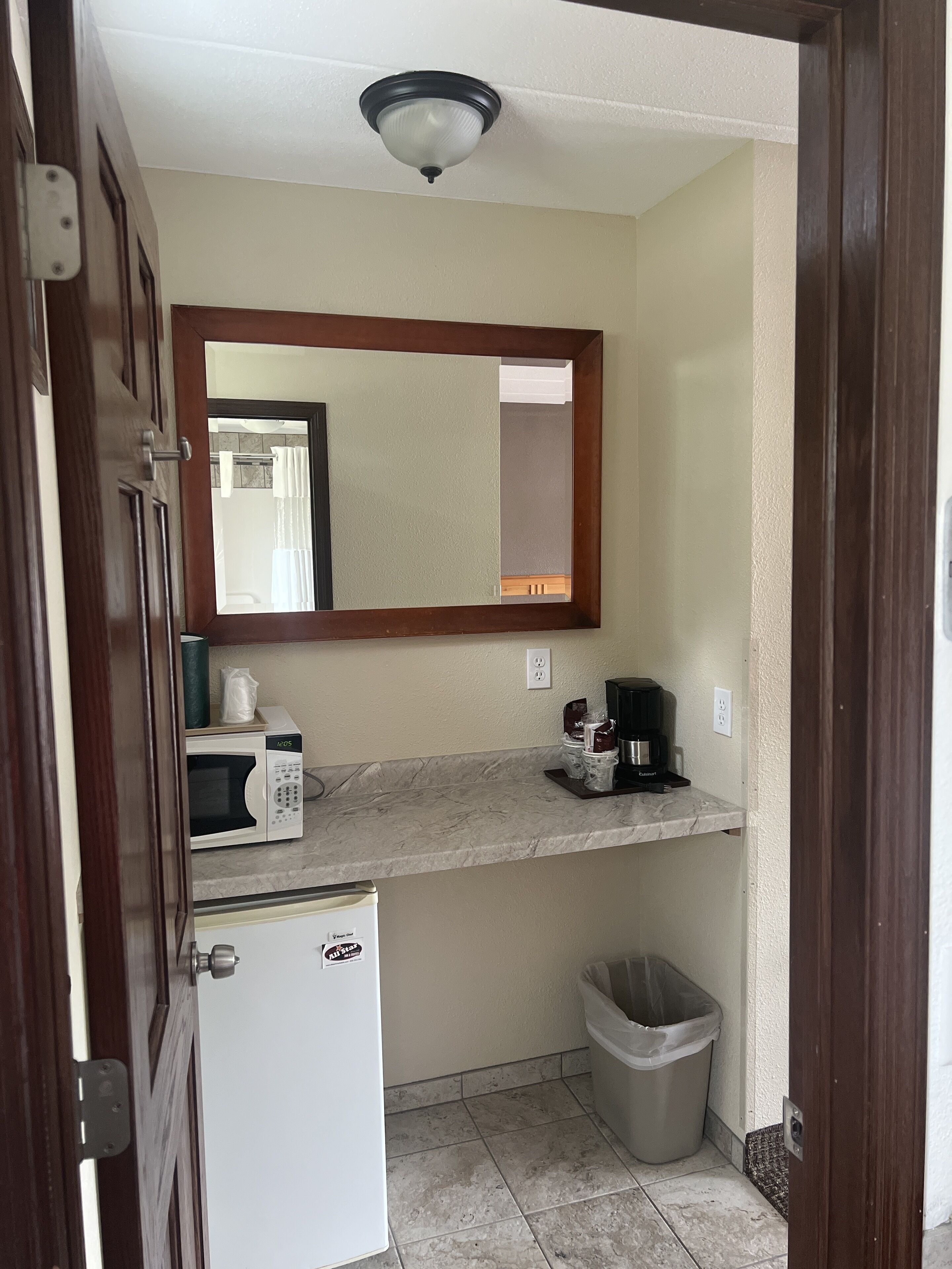 Uma cozinha compacta equipada com micro-ondas, cafeteira e lixeira.