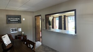 A dining area with a wooden table, chairs, a menu holder, and a wall-mounted sign that reads "KITCHEN."