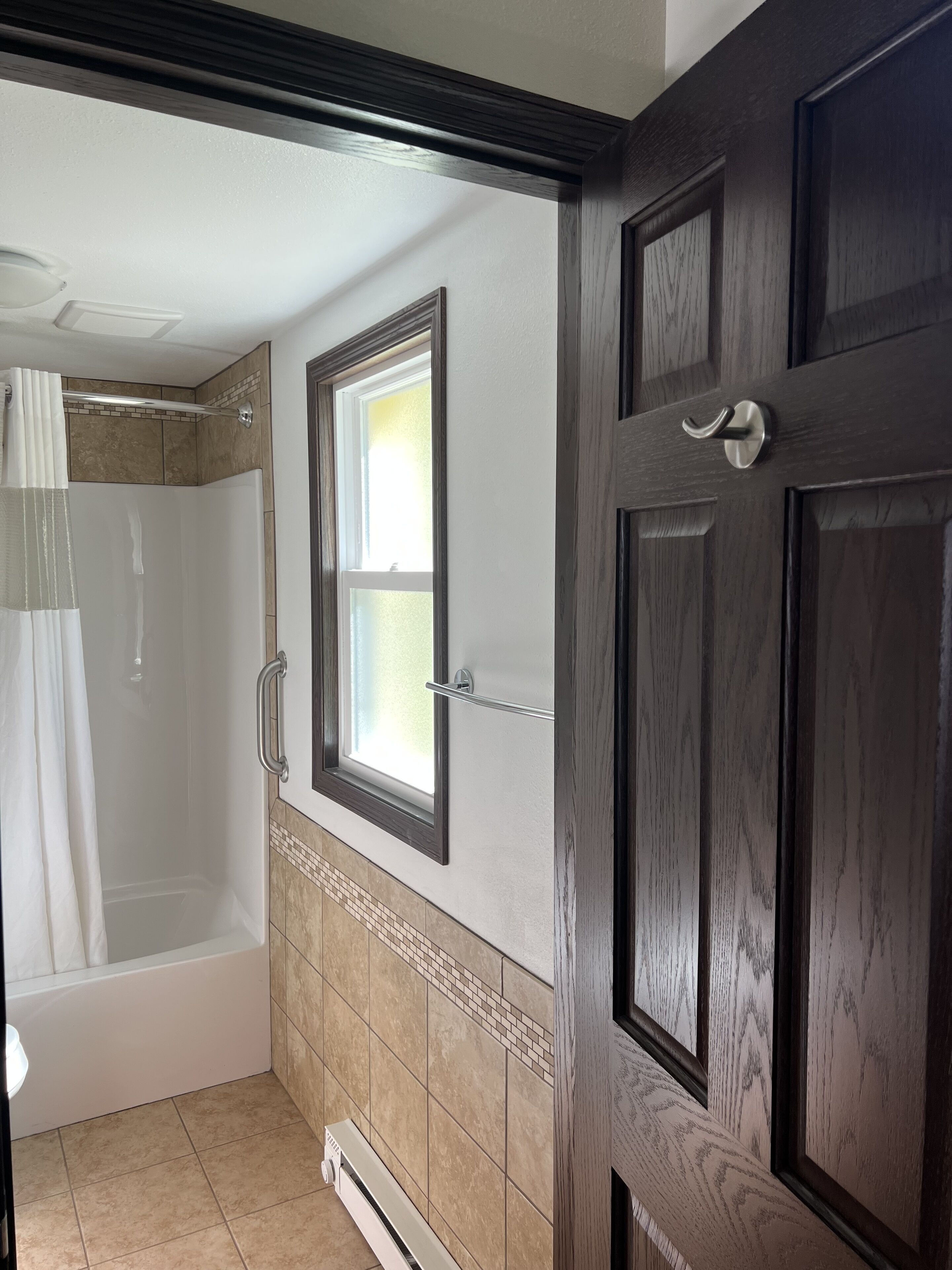 A bathroom with a shower, a bathtub, and a window.