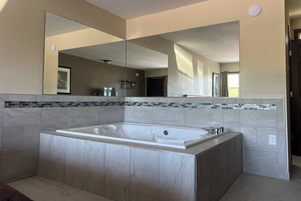 Une salle de bain moderne avec une grande baignoire sur pieds, un grand miroir et un mur recouvert de carreaux.