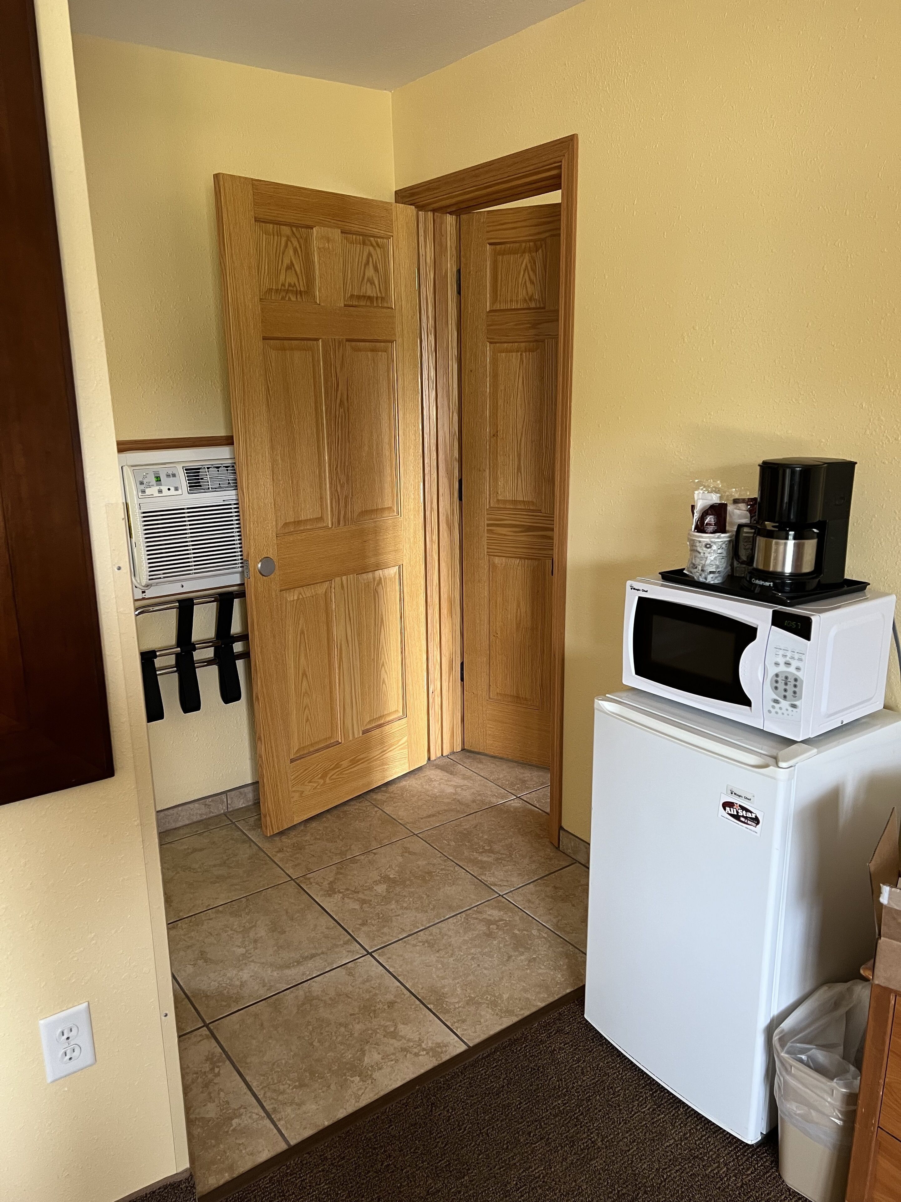 A compact kitchen with a microwave, coffee maker, and a refrigerator.