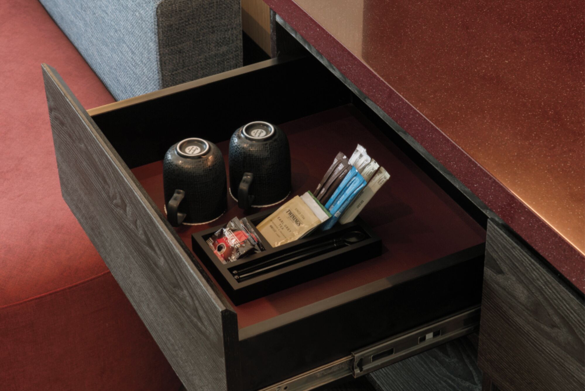 A drawer with two black containers, a tray with magazines, and a small box.