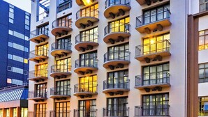 A multi-story hotel with balconies, a visible restaurant, and a parking area. - Quest Atrium Serviced Apartments (Wellington)