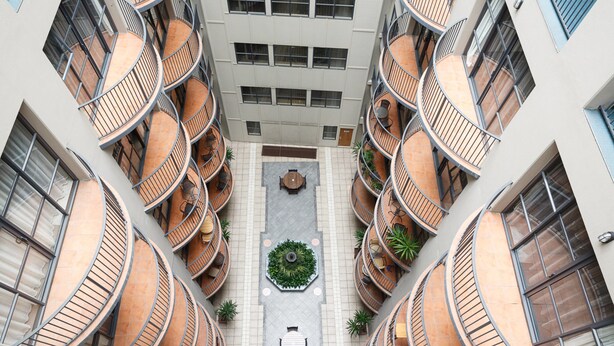 A multi-story building with balconies, a central courtyard with a seating area, and a small garden. - Quest Atrium Serviced Apartments (Wellington)