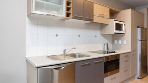 A modern kitchen with stainless steel appliances, a dishwasher, and a microwave. - Quest Atrium Serviced Apartments (Wellington)