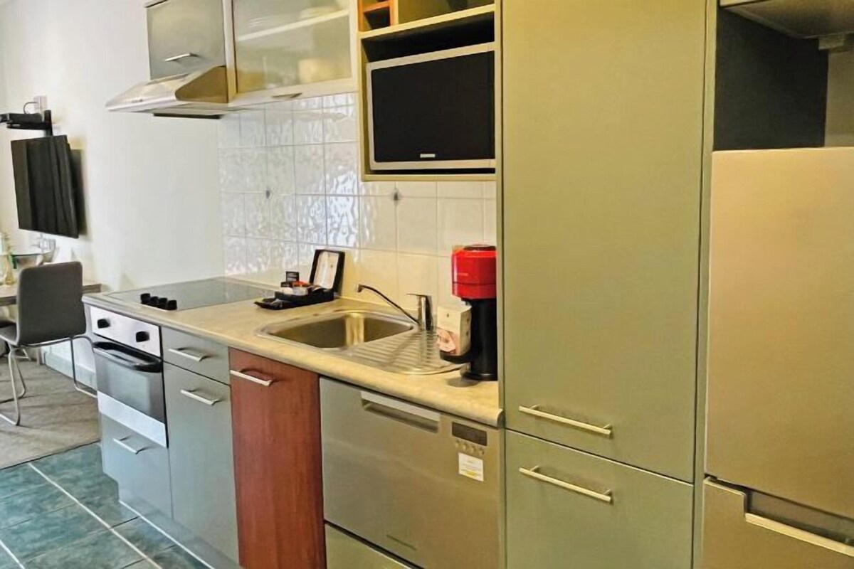 Una cucina compatta con elettrodomestici in acciaio inossidabile, un forno a microonde integrato e un lavandino.