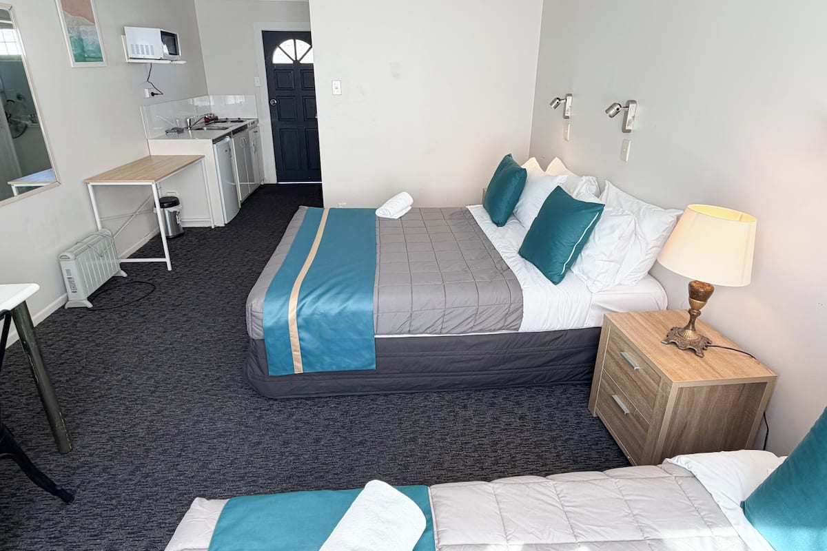 A hotel room with a bed, bedside table, lamp, and a desk with a chair.